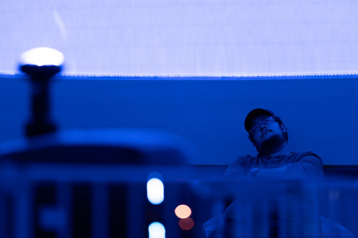 A University of Montana student in a baseball hat and eyeglasses sits, leaning back and watching a show in UM's Planetarium on the University of Montana campus.