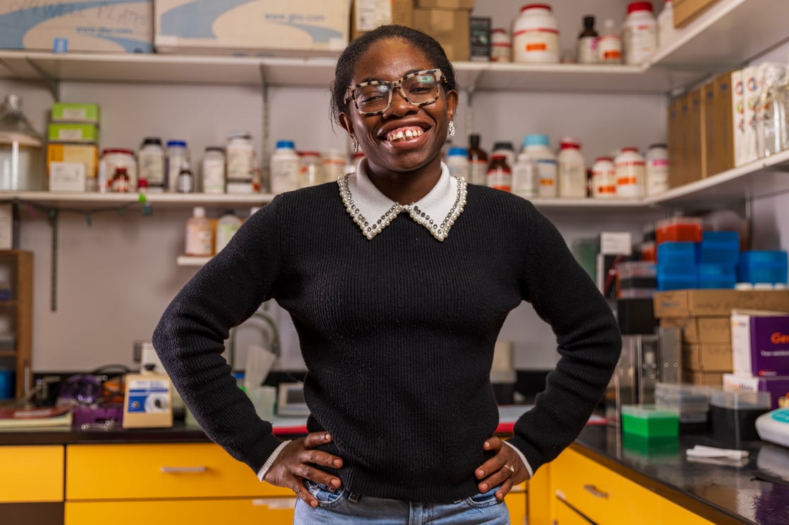 Deborah Agbakwuru in her lab on campus. There are shelves and countertops full of research material in the background. 