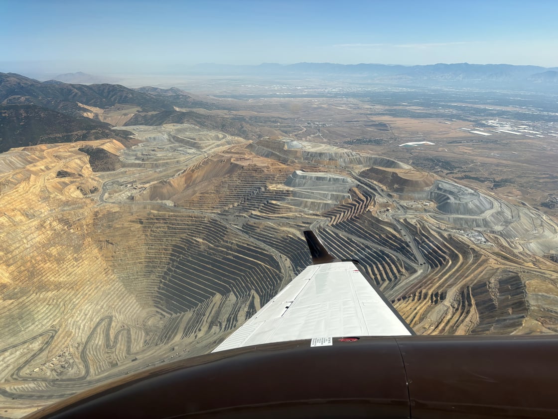 Wing of airplane and high-altitude view of an open pit mine near Salt Lake City