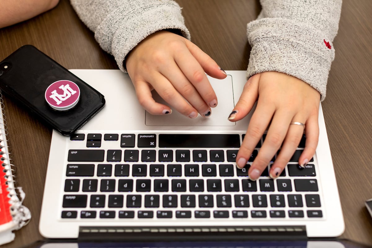 Hands typing on a laptop keyboard